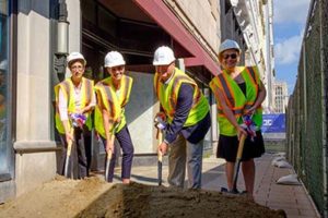 Four people dig shovels into a mound of dirt at the Elliott groundbreaking